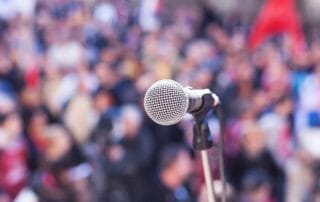 A microphone before a crowd waiting for a memorable speaker